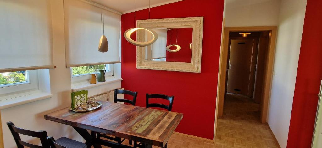 een eetkamer met een houten tafel en een rode muur bij Wohlfühlen & Arbeiten in Toplage mit gratis Tiefgaragenplatz in Graz