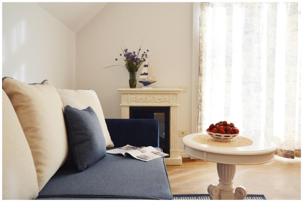 ein Wohnzimmer mit einem blauen Sofa und einem Tisch in der Unterkunft Smėlynas Neringa Apartments in Neringa