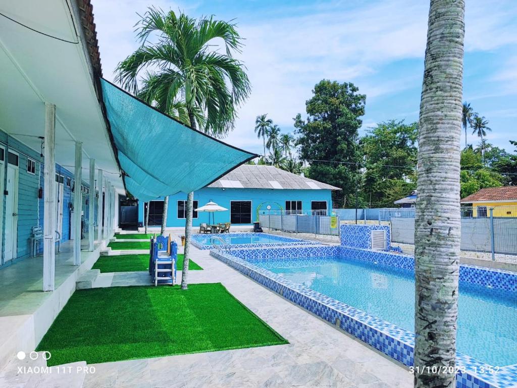 a swimming pool with a palm tree next to a house at Green Forest Resort in Setiu