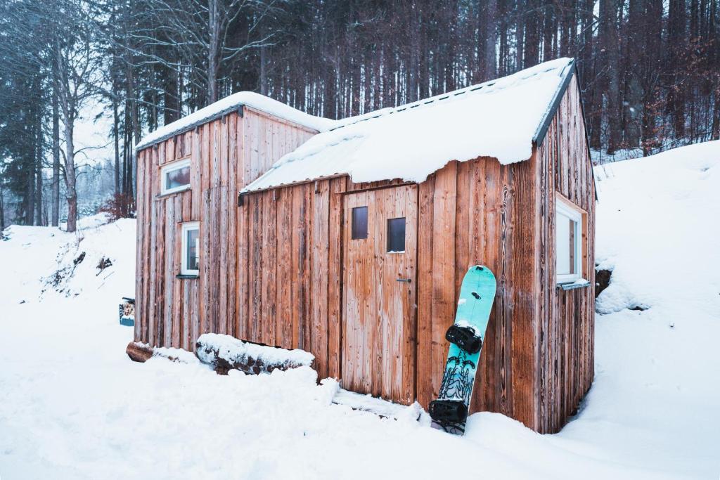 a wooden building with a snowboard in the snow at maringotka schovanka in Malá Morávka