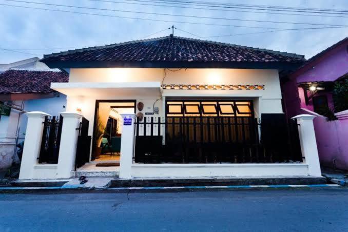 a small white house with a black gate at Good Feeling Hostel in Banyuwangi