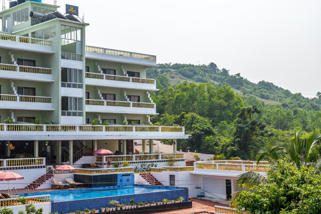 a hotel with a swimming pool in front of a mountain at SPARV Aulakhs Resort in Mandrem