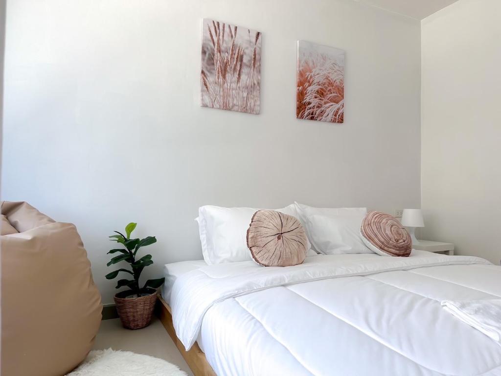 um quarto com uma cama branca e duas fotografias na parede em BAOBAB em Praia de Patong