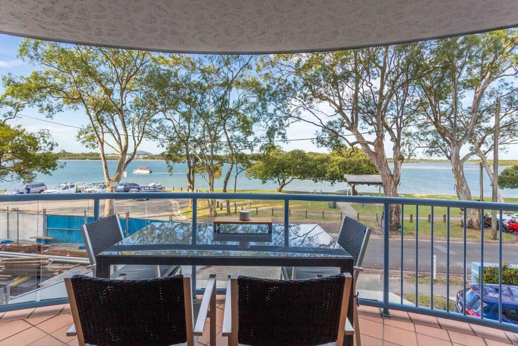 Un balcón con mesa y sillas y vista al agua. en Maroochydore Riverfront, en Maroochydore