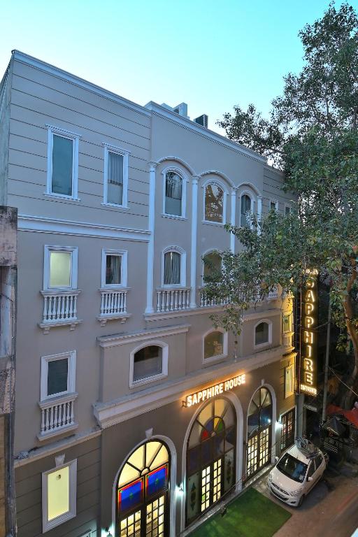 Hotel Sapphire House - 3 Mins Walk from Metro and 5 Mins from Rail Station, a white building with a car parked in front of it at Hotel Sapphire House - 3 Mins Walk from Metro and 5 Mins from Rail Station in New Delhi