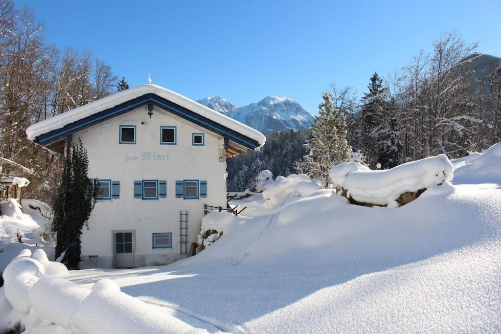 ein schneebedecktes Gebäude mit Bäumen und Bergen in der Unterkunft Alte Mühle mit wunderbarem Bergblick in Ramsau bei Berchtesgaden