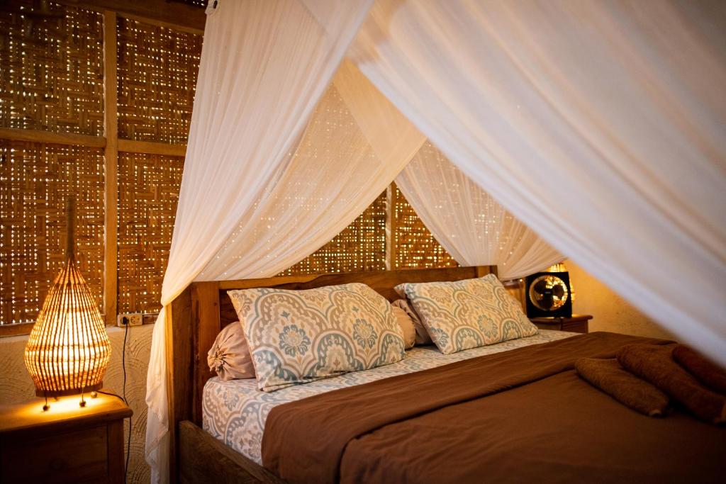 a bedroom with a canopy bed and a window at Rinjani Lighthouse in Senaru