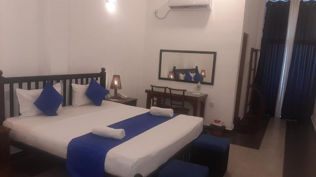 a bedroom with a large bed with blue pillows at Alnaro Hotel & Resort in Moratuwa