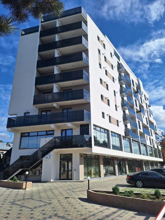 a large white building with a car parked in front at Deluxe Apartments on G Enescu Blvd near Stefan Cel Mare University Suceava in Suceava