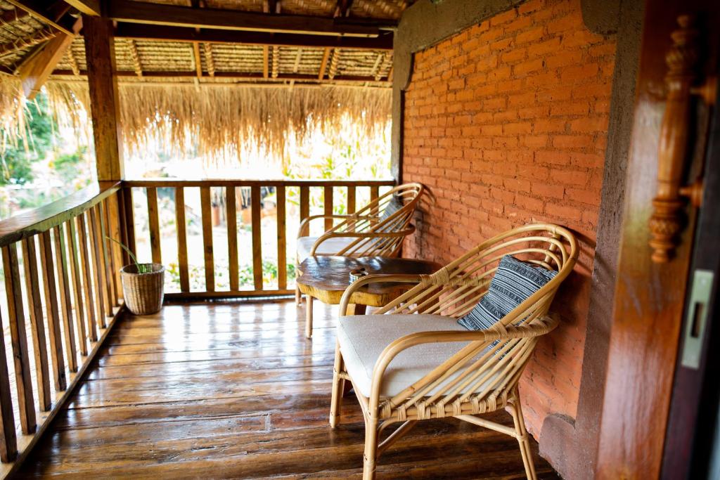 a porch with two chairs and a table on a balcony at Rinjani Lighthouse in Senaru