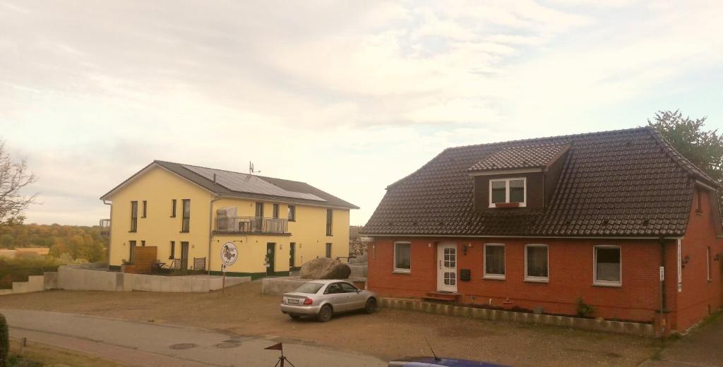 two houses and a car in a parking lot at Pension Rabe Haus Retzi Rabe in Grevesmühlen