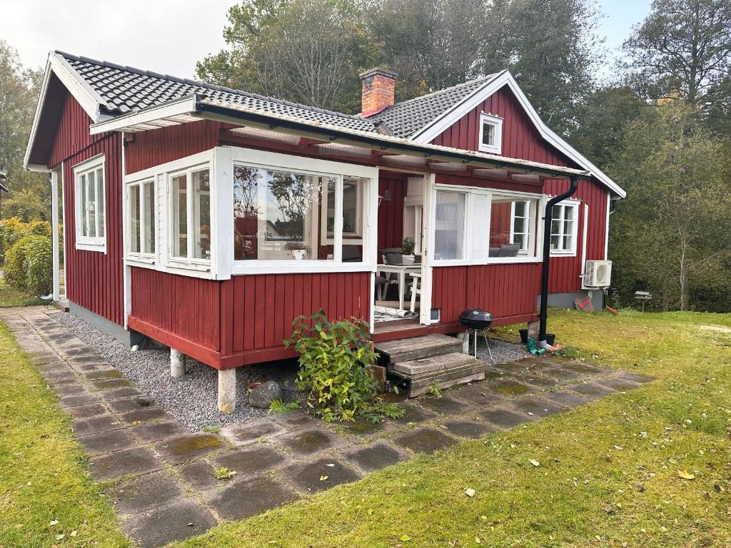 une maison rouge avec des fenêtres blanches et une véranda dans l'établissement Nice red cottage near the lake Hjalmaren and Vingaker, à Vingåker