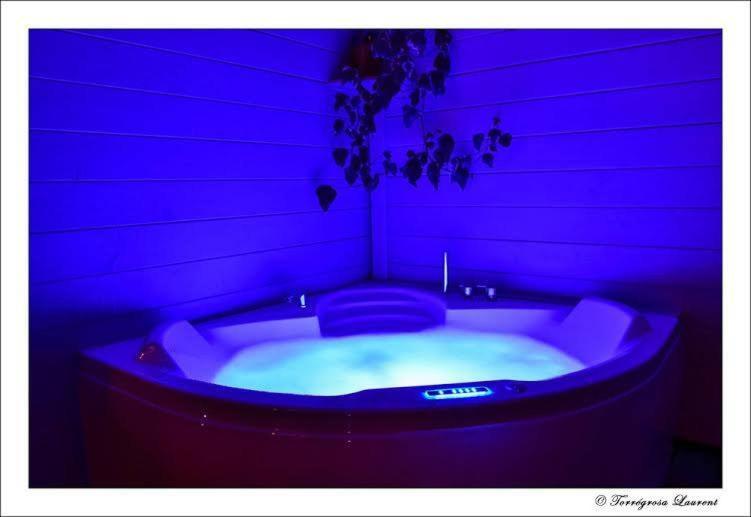 Dournazac的住宿－Bulle d'R，紫色灯的客房内的按摩浴缸