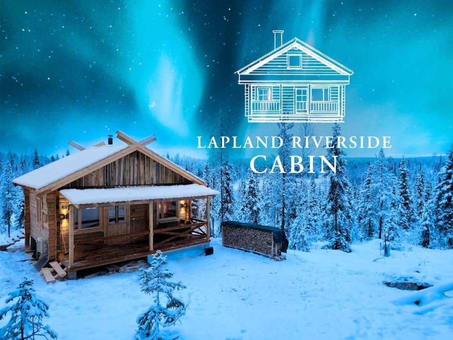 een blokhut in de sneeuw met het noorderlicht bij Lapland Riverside Cabin, Äkäsjoen Piilo - Jokiranta, Traditional Sauna, Avanto, WiFi, Ski, Ylläs, Erä, Kala in Äkäsjoensuu