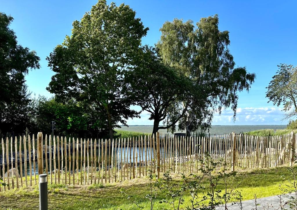 uma cerca de madeira com uma árvore ao fundo em Ferienwohnung Baltic Lagoon Ostsee em Fuhlendorf