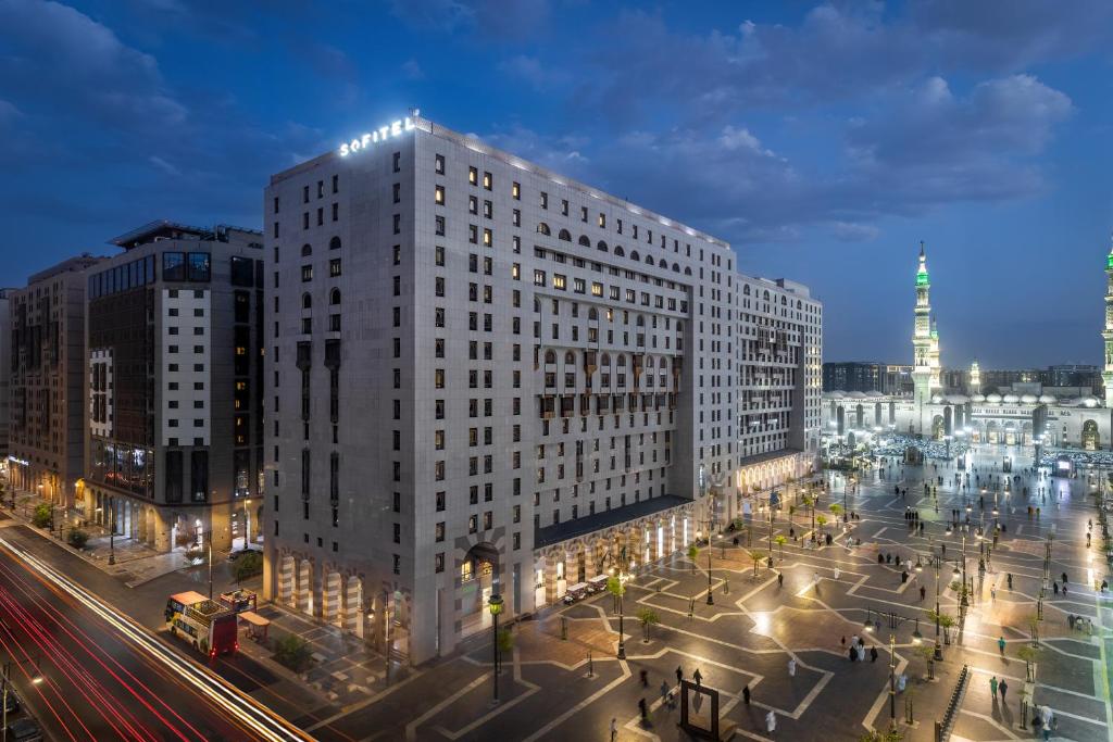 un edificio blanco alto en una calle de la ciudad por la noche en Sofitel Shahd Al Madinah, en Medina