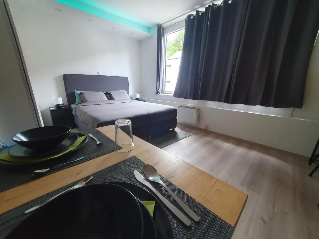 Un dormitorio con una cama y una mesa y una ventana. en Le Cosy - Queen-size, full équipé, wifi, parking, en Namur