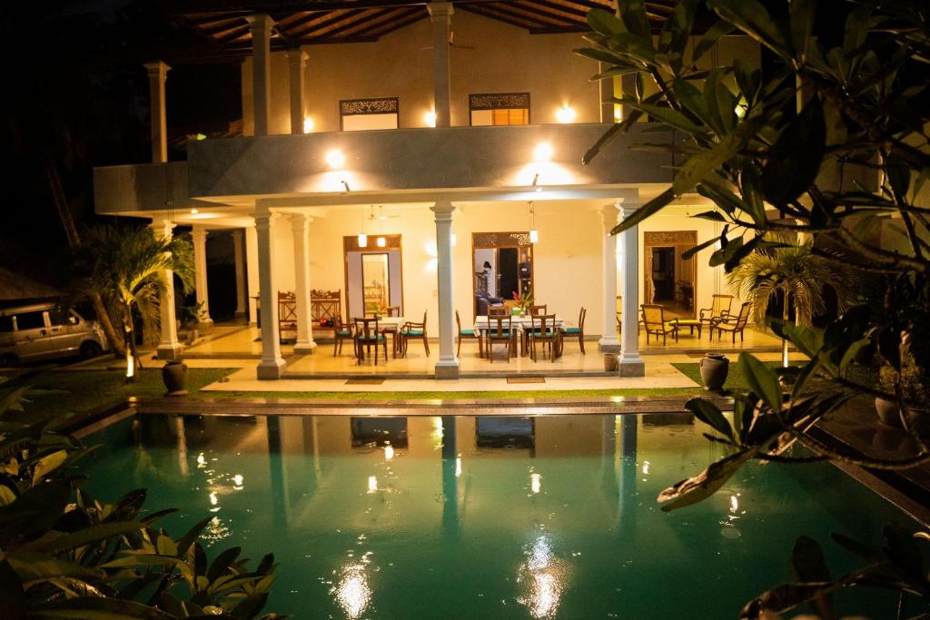 a house with a swimming pool at night at New Mangosteen Garden Villa in Hikkaduwa