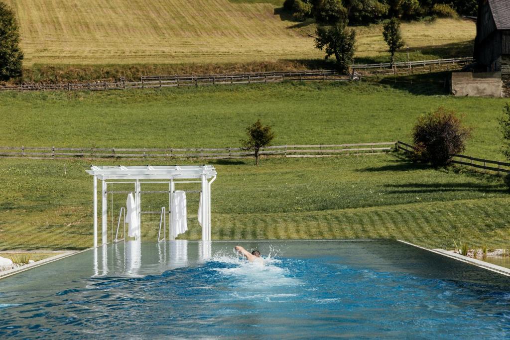 a person swimming in a pool with a white table at Thermenwelt Hotel Pulverer in Bad Kleinkirchheim