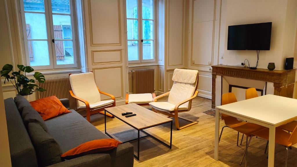 - un salon avec un canapé, des chaises et une télévision dans l'établissement Appartement de Louise et Adrien, à Gray