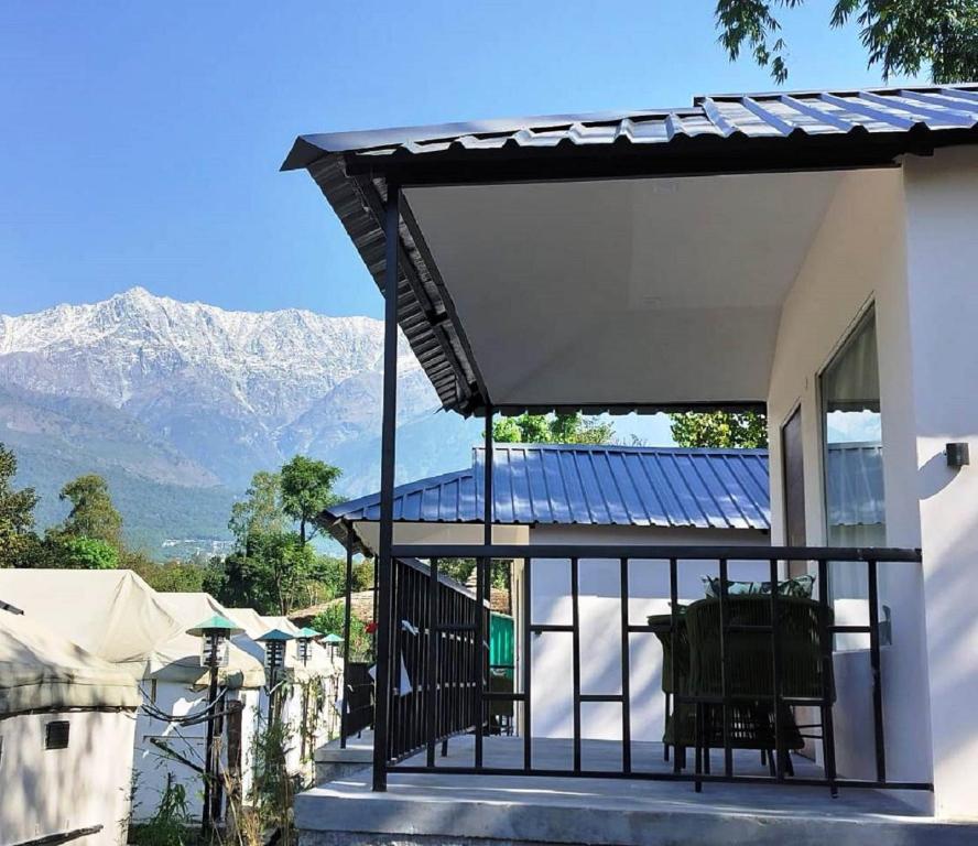 a house with a solar roof with mountains in the background at Dev Bhoomi Farms & Cottages in Dharamshala