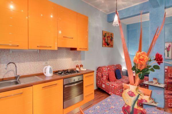 ローマにあるOlimpia Apartmentのキッチン(オレンジ色のキャビネット、赤いソファ付)