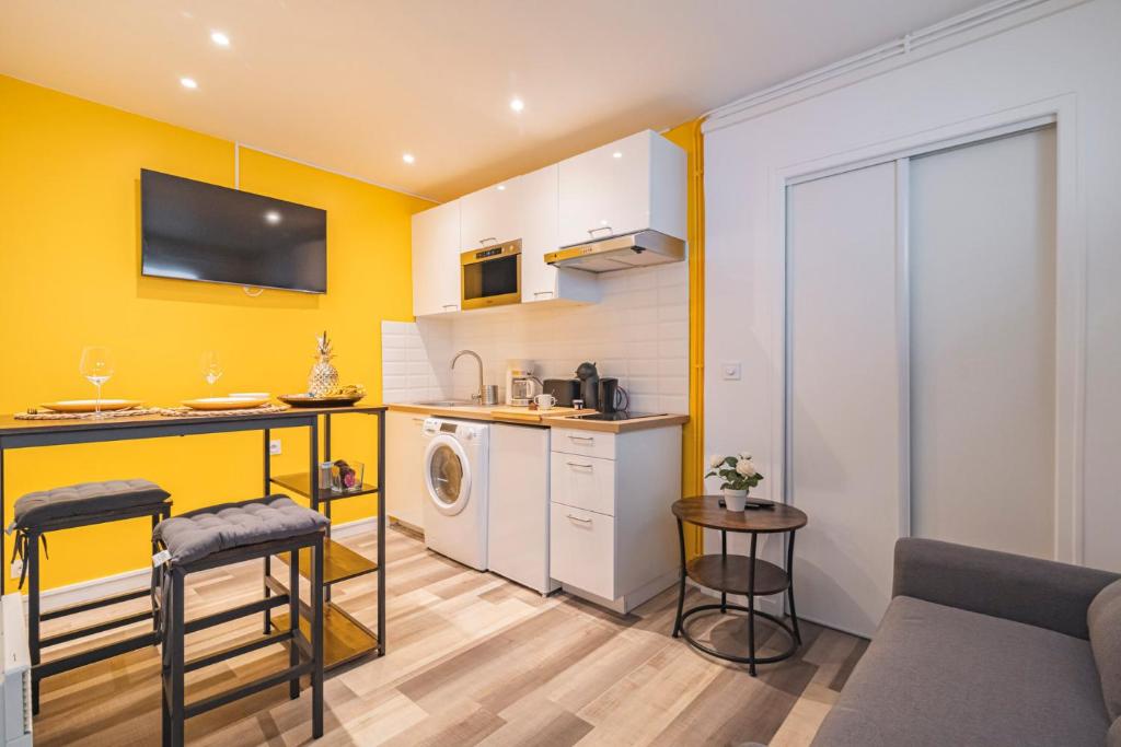 a kitchen with yellow walls and a living room at Pauline's Home Gambetta in Reims