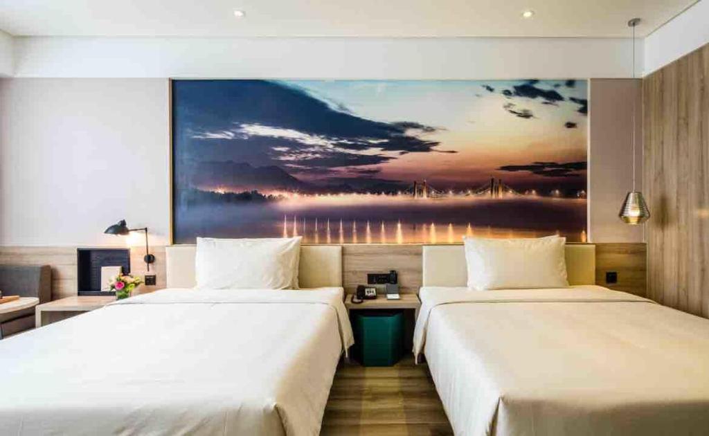 2 Betten in einem Hotelzimmer mit Wandgemälde in der Unterkunft Atour Hotel Hangzhou Xiaoshan Peoples Square in Hangzhou