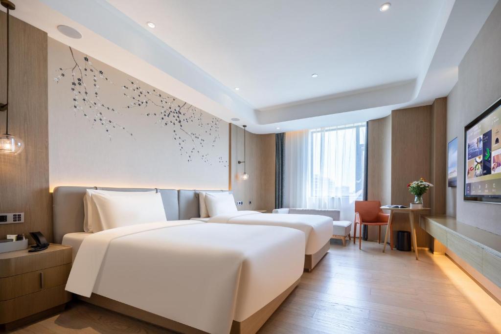 2 Betten in einem Hotelzimmer mit Wandgemälde in der Unterkunft Atour X Hotel Shanghai Jinshan Wanda Plaza City Beach in Jinshan