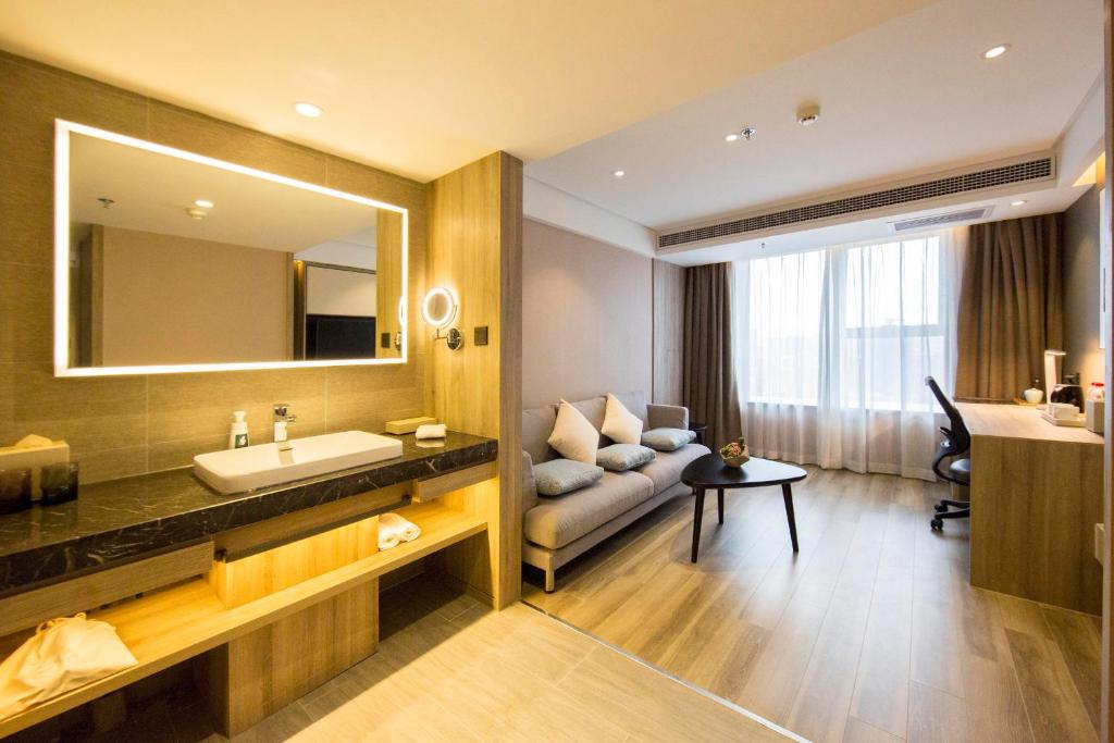 bagno con divano, lavandino e specchio di Atour Hotel Shenyang Olympic Yingpan Street a Shenyang