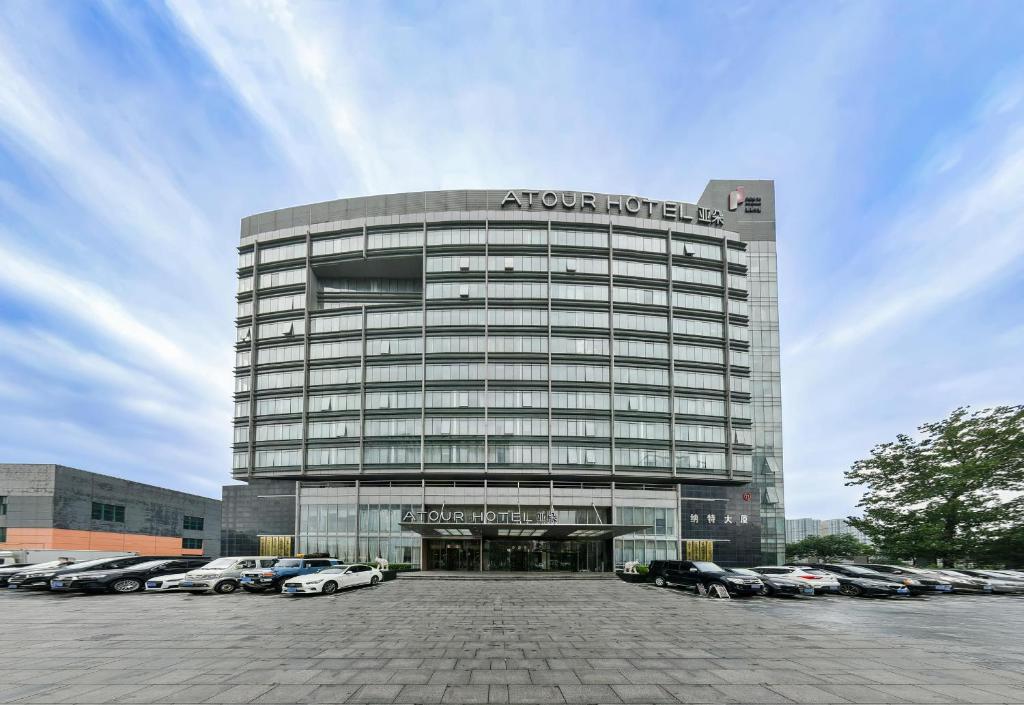 a large building with cars parked in a parking lot at Atour Hotel Beijing Yizhuang New Town Majuqiao in Daxing