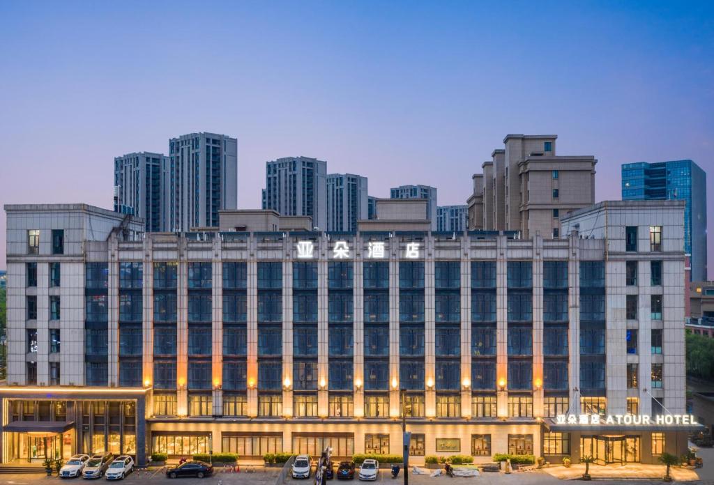 Atour Hotel Hangzhou Xintiandi Zhongda Intime في هانغتشو: مبنى كبير به سيارات تقف في موقف للسيارات