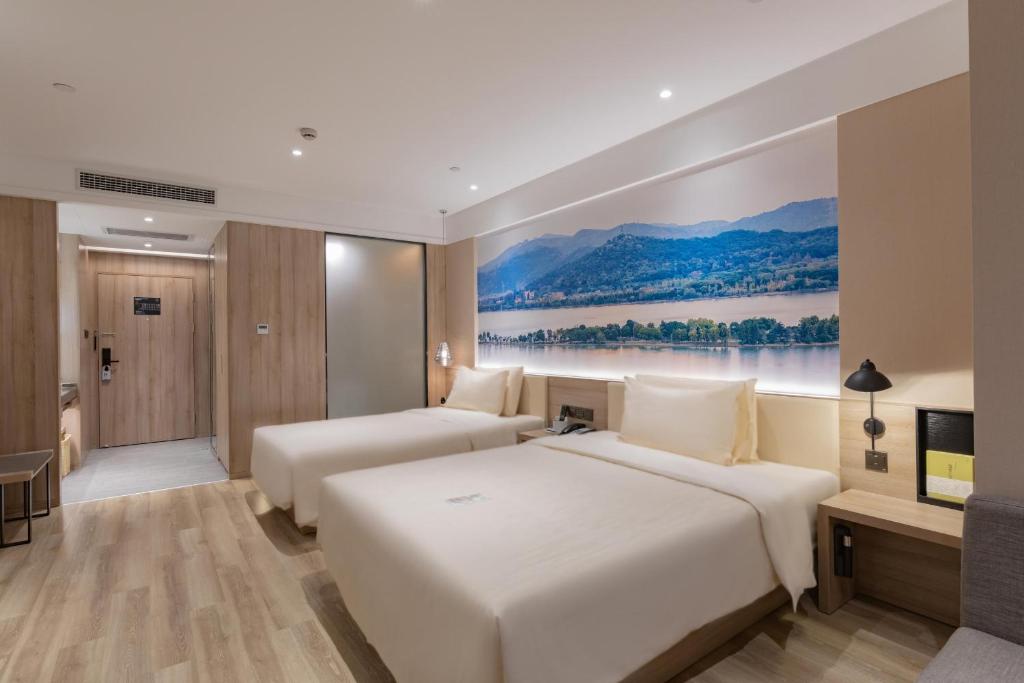 two beds in a hotel room with a painting on the wall at Atour Hotel Chaozhou Ancient Town People's Square in Chaozhou
