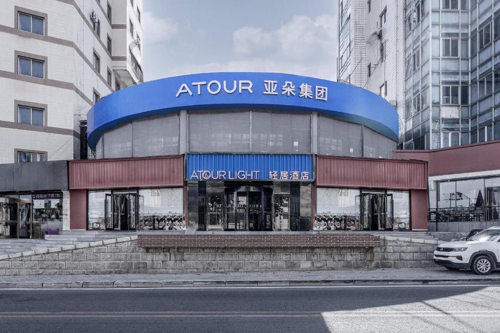 a building with a car parked in front of it at Atour Light Hotel Dalian Xinghai Plaza Shengya Ocean World in Dalian