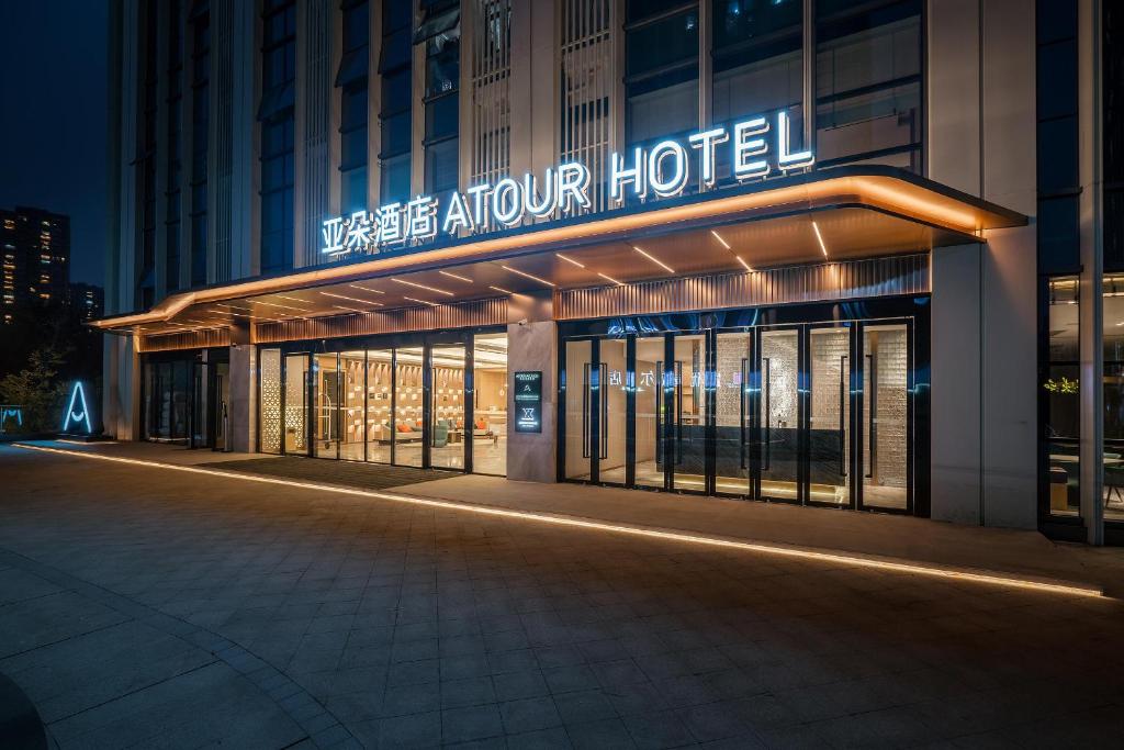 ein Hotelgebäude mit einem Schild am Abend in der Unterkunft Atour Hotel Chengdu East Station Greenland 468 Center in Chengdu