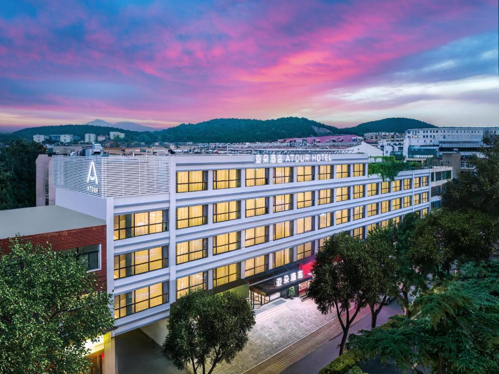 an office building with a sunset in the background at Atour Hotel Jinan Shungeng Covention and Exhibition Center Bayi Overpass in Jinan