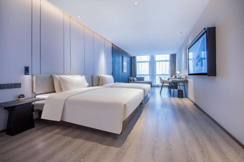 済南市にあるAtour Hotel Jinan Huashan Huanyu Cityのベッド2台とテレビが備わるホテルルームです。