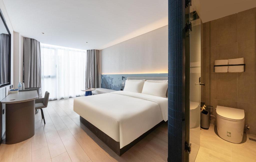 a hotel room with a white bed and a desk at Atour Light Hotel Jinan Harmony Square Provincial Hospital in Jinan