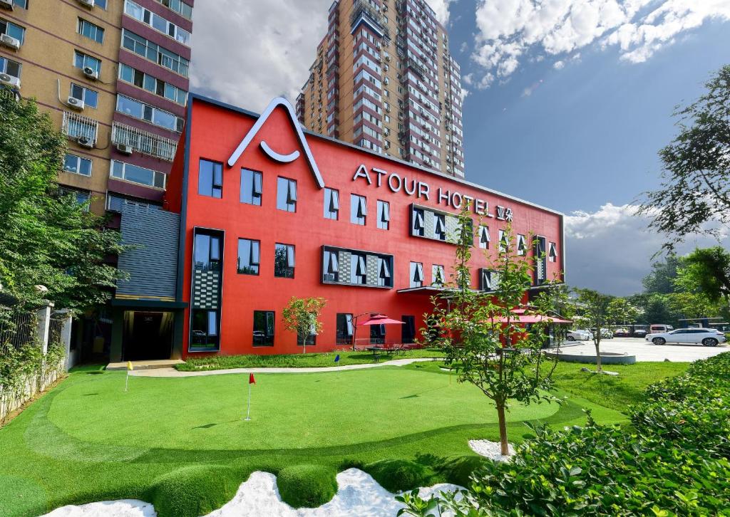 a red building with a golf course in front of it at Atour Hotel Beijing Wangjing Science and Technology Park in Beijing