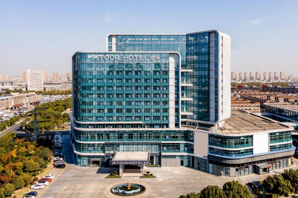 un edificio de cristal alto con un cartel. en Atour Hotel Changzhou Wujin Science and Education City en Changzhou