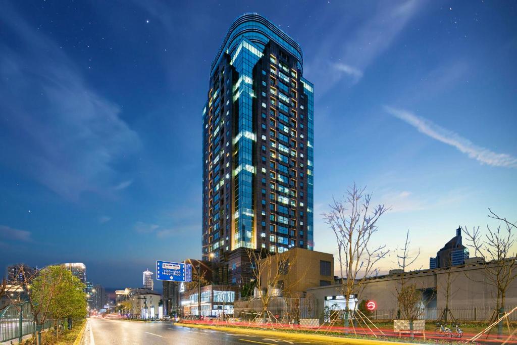 um edifício azul alto numa rua da cidade à noite em Atour Hotel Shanghai Lujiazui Pudong Avenue em Xangai