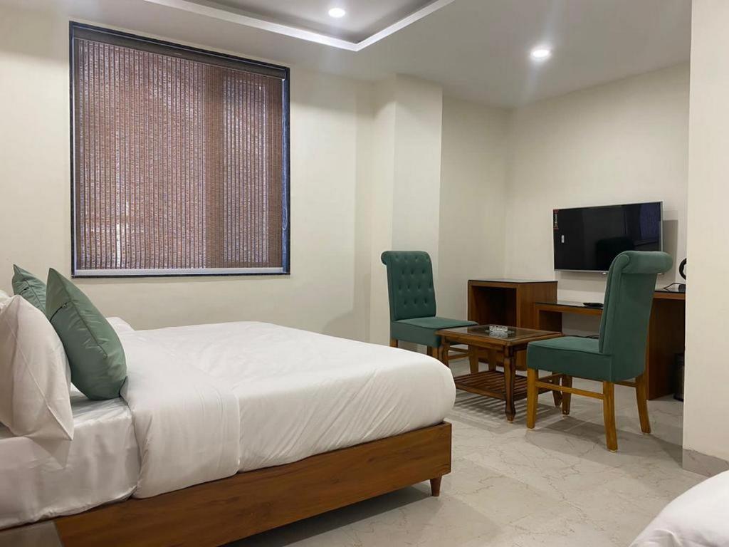 a bedroom with a bed and a desk and a television at Hotel Heera Residency in Bhopal