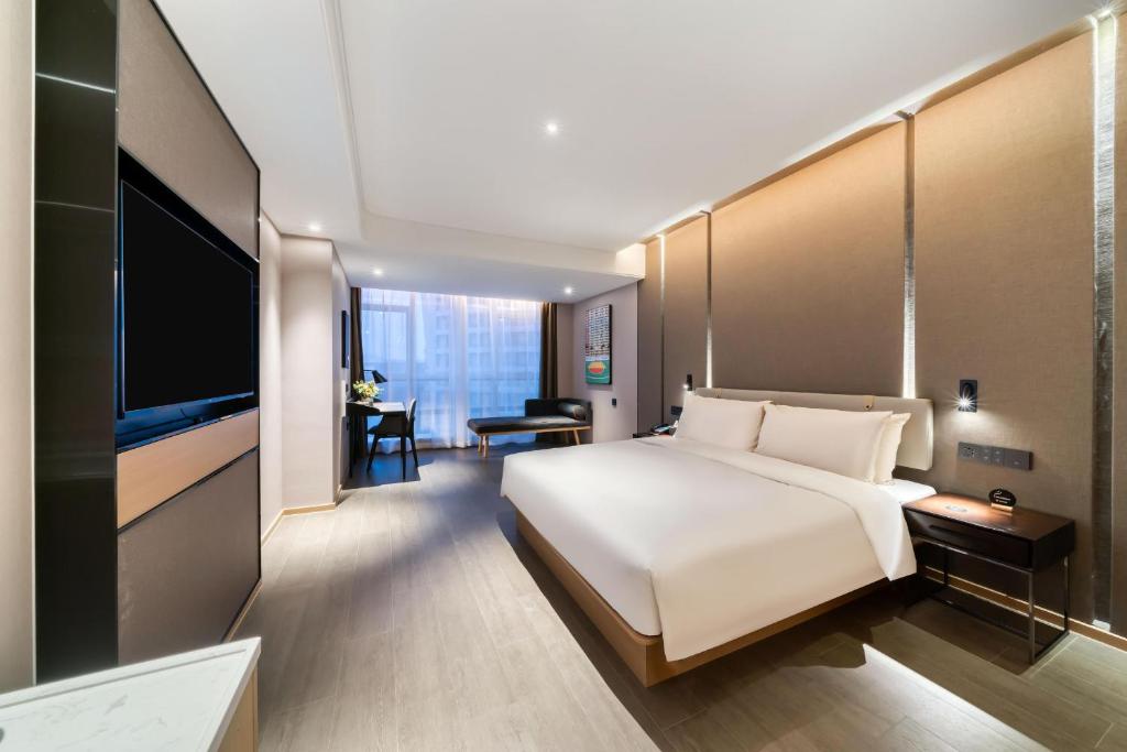 杭州的住宿－杭州滨江宝龙城亚朵酒店，卧室配有一张白色大床和一台平面电视。