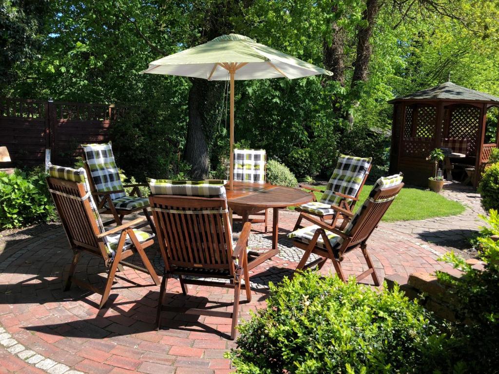 a table and chairs with an umbrella on a brick patio at NEU! Ferienhaus Johann an der Nordsee in Dornum