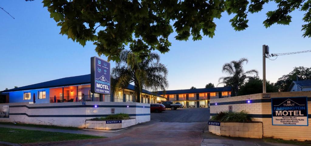 a hotel with a sign in front of a building at Tumut Farrington motel in Tumut