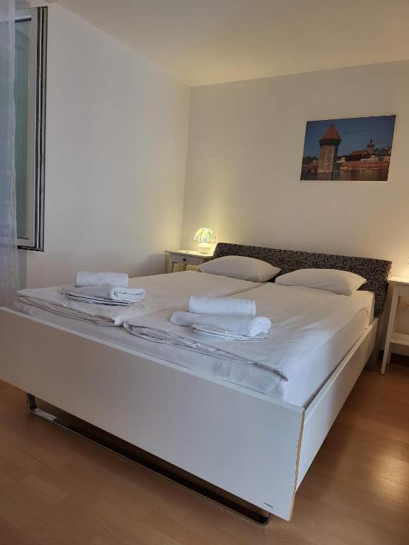 una camera da letto con un grande letto bianco con lenzuola bianche di Bastis Central Guesthouse Lucerne City a Lucerna