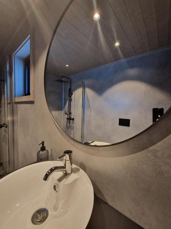 a bathroom with a sink and a round mirror at Varanger View in Vardø