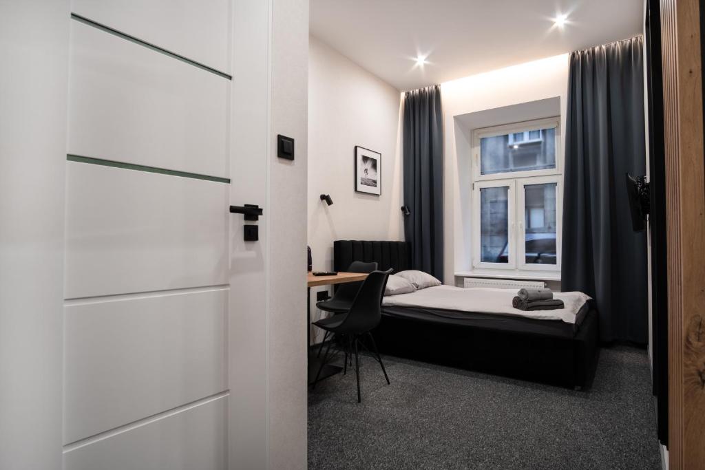 um quarto com uma cama, uma secretária e uma janela em Dream Aparts - Piotrkowska 33 em Lódź