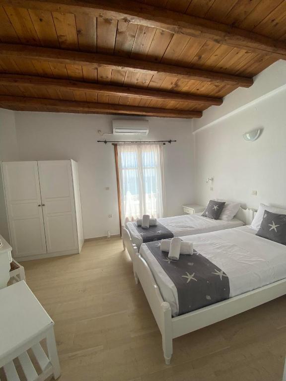a bedroom with two beds and a wooden ceiling at Fisilanis Beachfront Hotel in Logaras