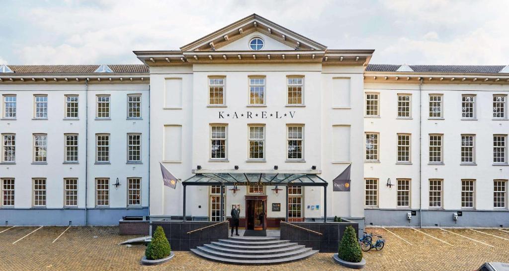 un grand bâtiment blanc avec une personne debout à l'extérieur dans l'établissement Grand Hotel Karel V, à Utrecht